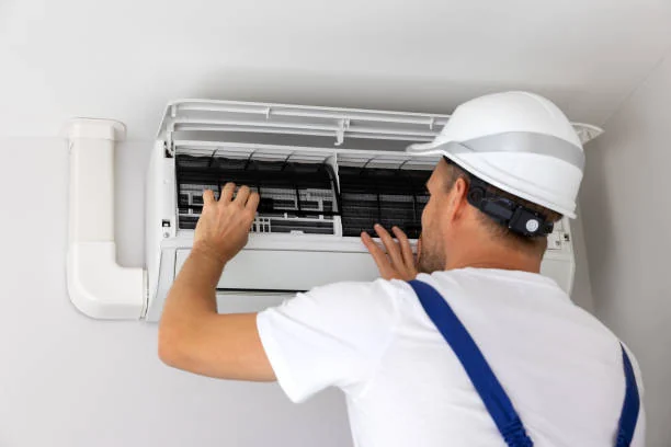 Technician fitting and checking a wall-mounted air-conditioning unit