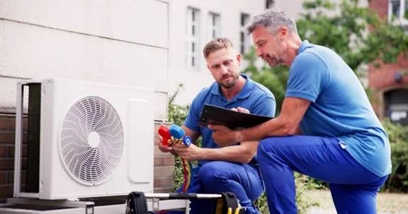 Two HVAC technicians discussing an outdoor system inspection