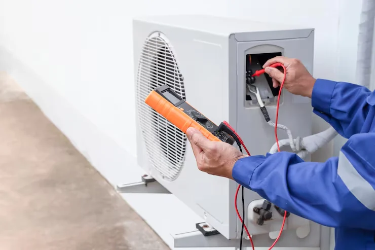 Technician diagnosing an outdoor HVAC unit using a multimeter